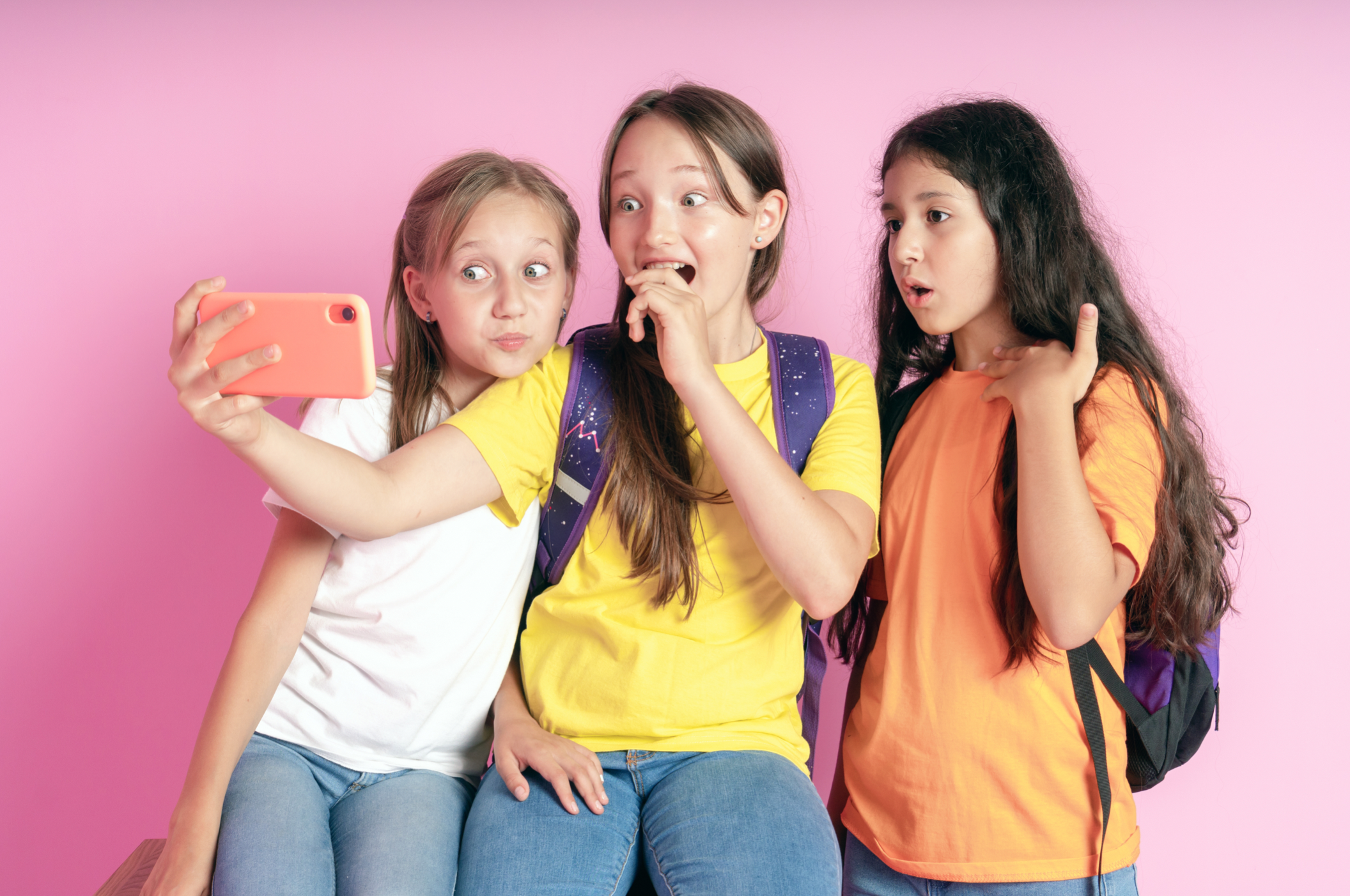 Three young girls pose in front of their phone camera